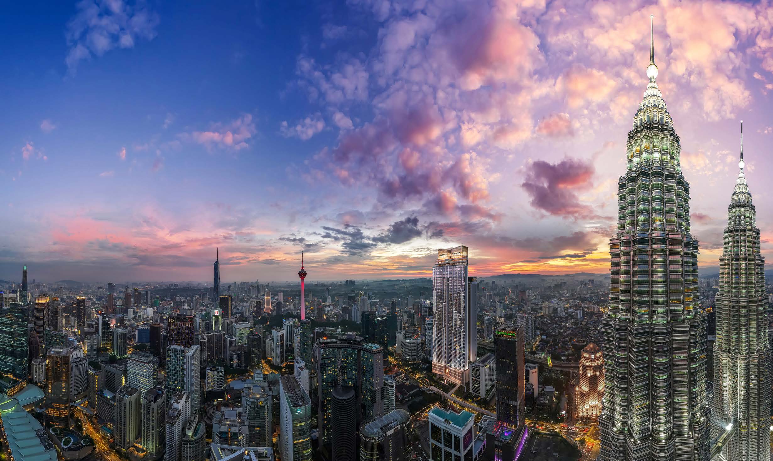 Artist's impression of the Armani Hallson KLCC tower rising against the Kuala Lumpur skyline at twilight, with the Petronas Twin Towers in view